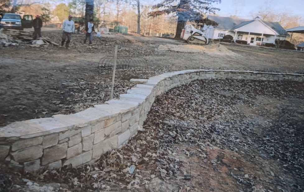 stone wall with flat cement top winding through yard