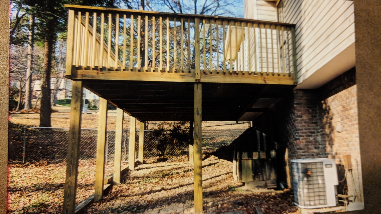 side view of second-story deck along back of house held up by beams around the deck's perimeter