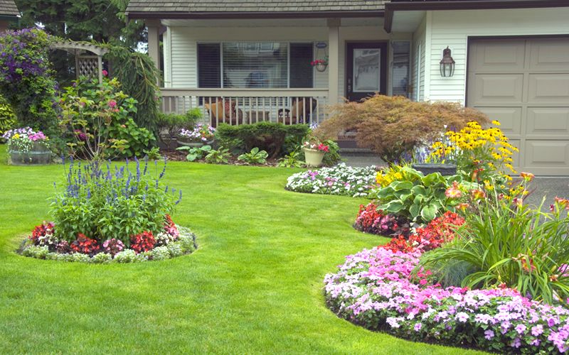 Flowery landscaped bed with stone border in front of house